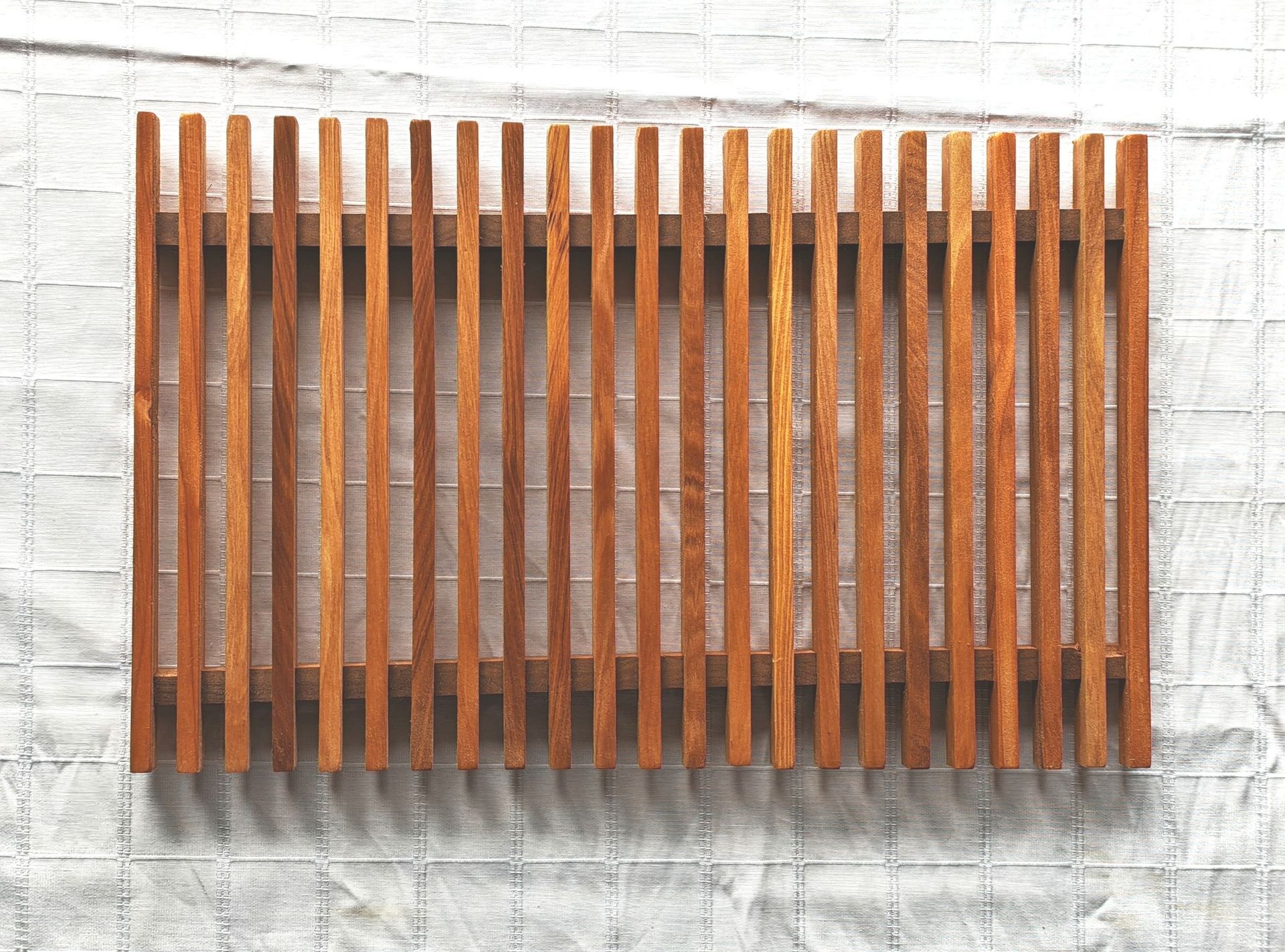 Una valla de madera cuelga de una pared de ladrillos.