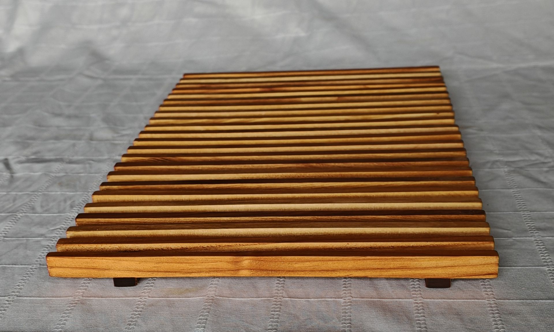 Una valla de madera cuelga de una pared de ladrillos.