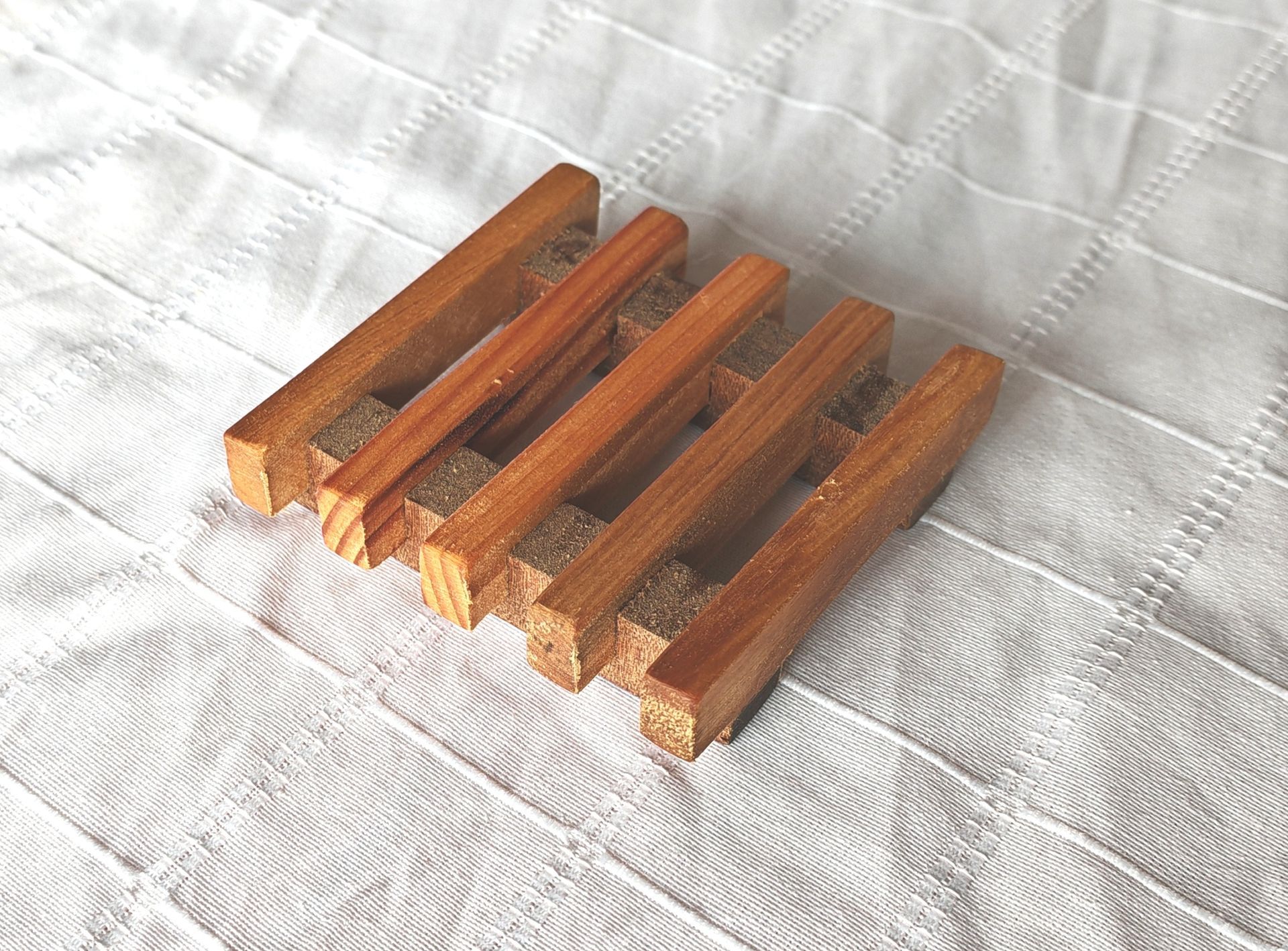 Una jabonera de madera reposa sobre una manta blanca.