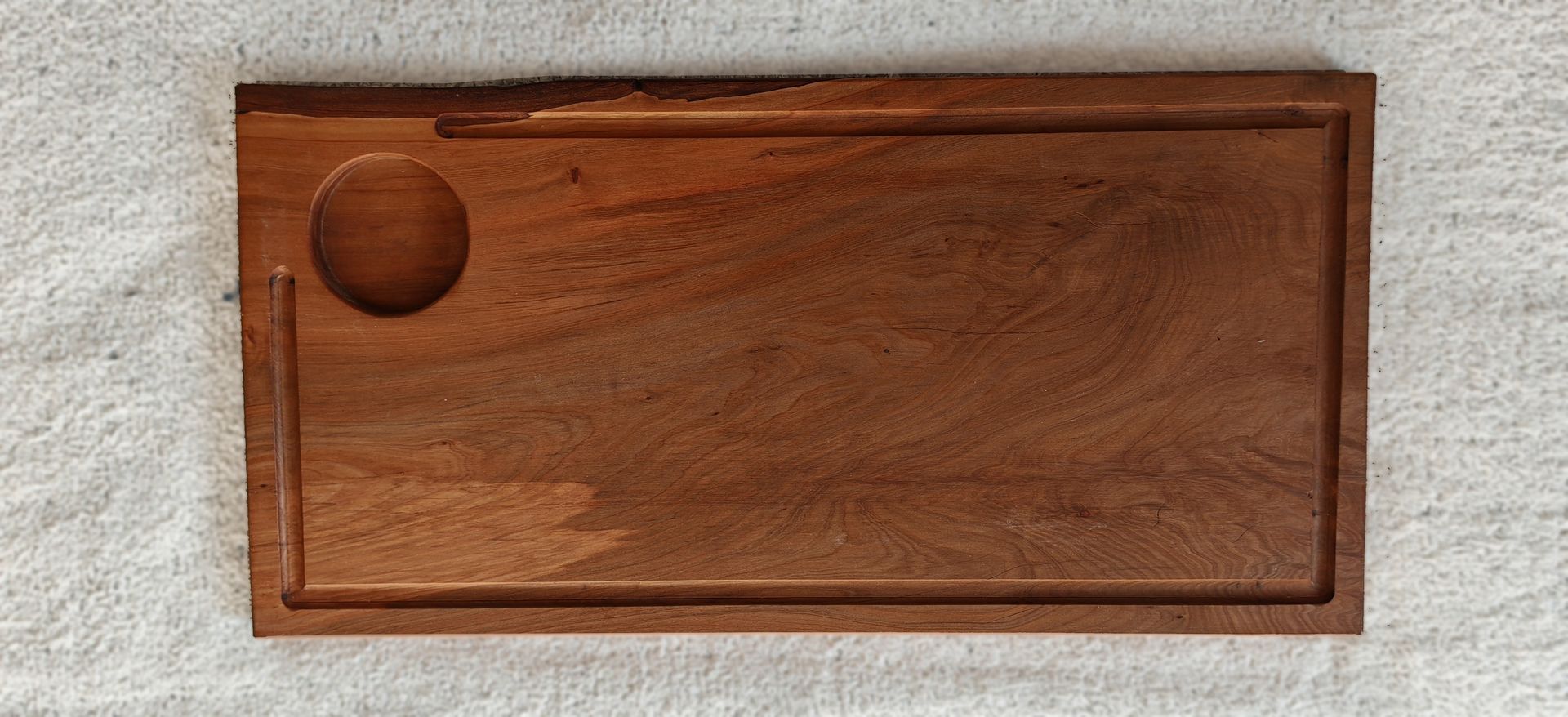 Una tabla de cortar de madera con un agujero en el medio está sobre una mesa.