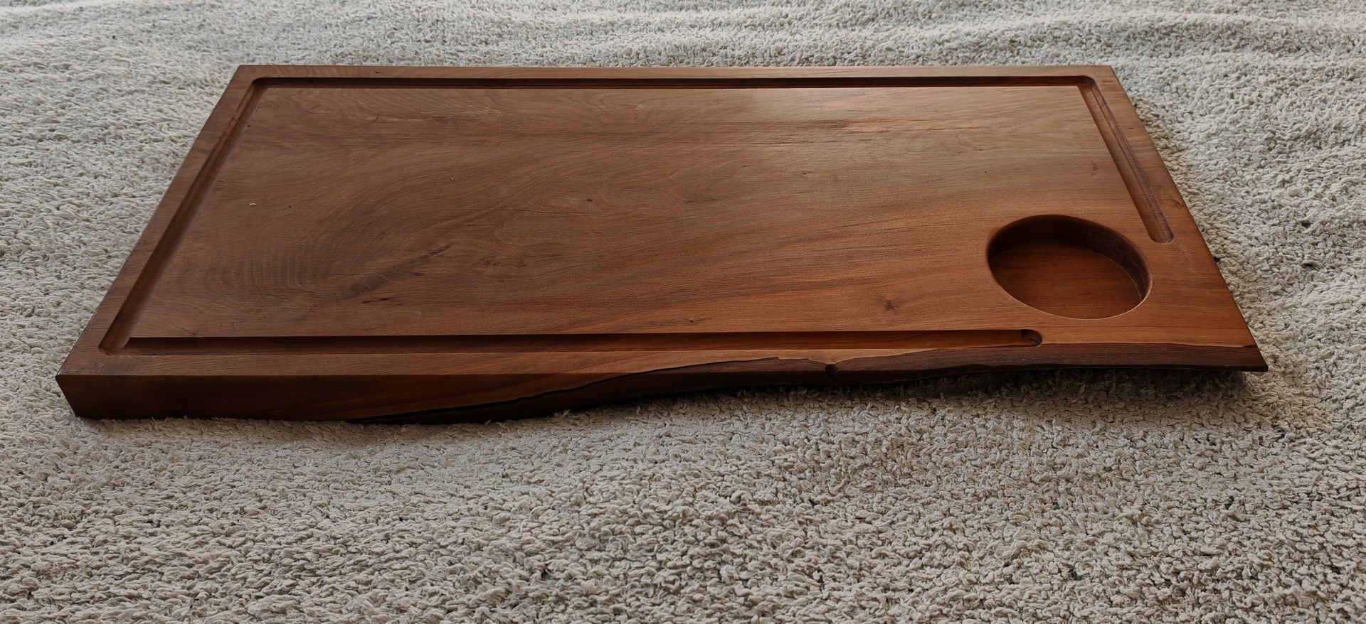 Una tabla de cortar de madera con un agujero en el medio está sobre una mesa.