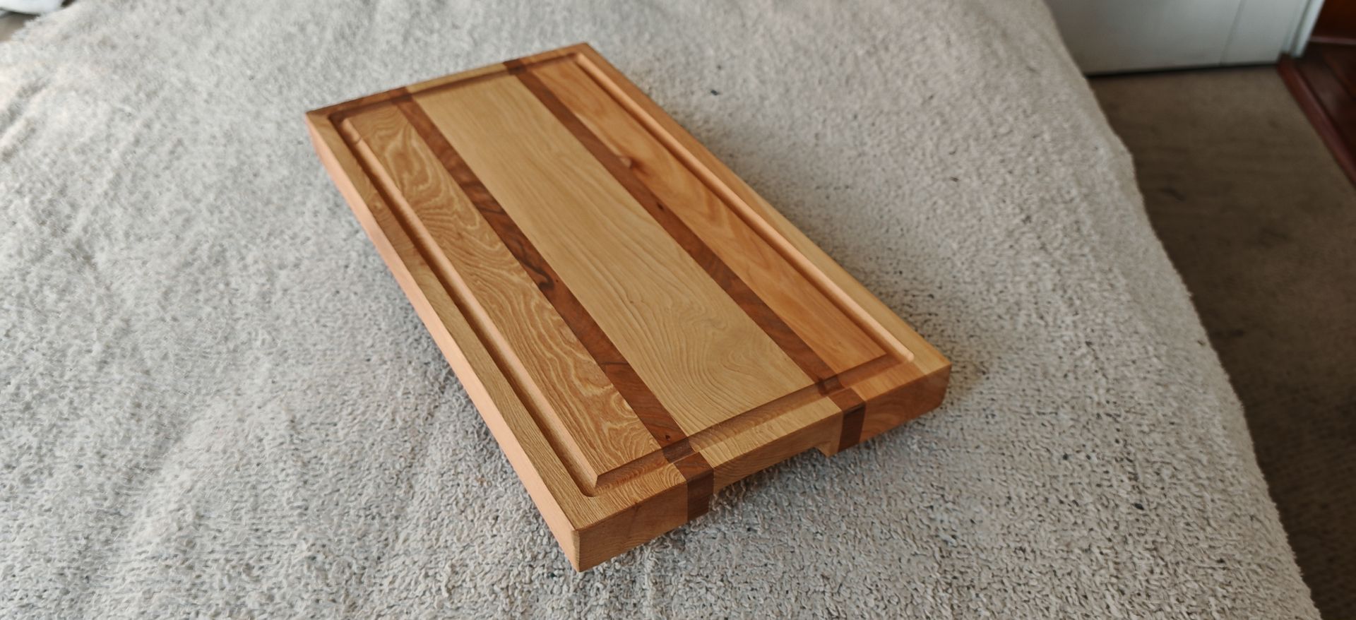 Una tabla de cortar de madera está encima de una cama.