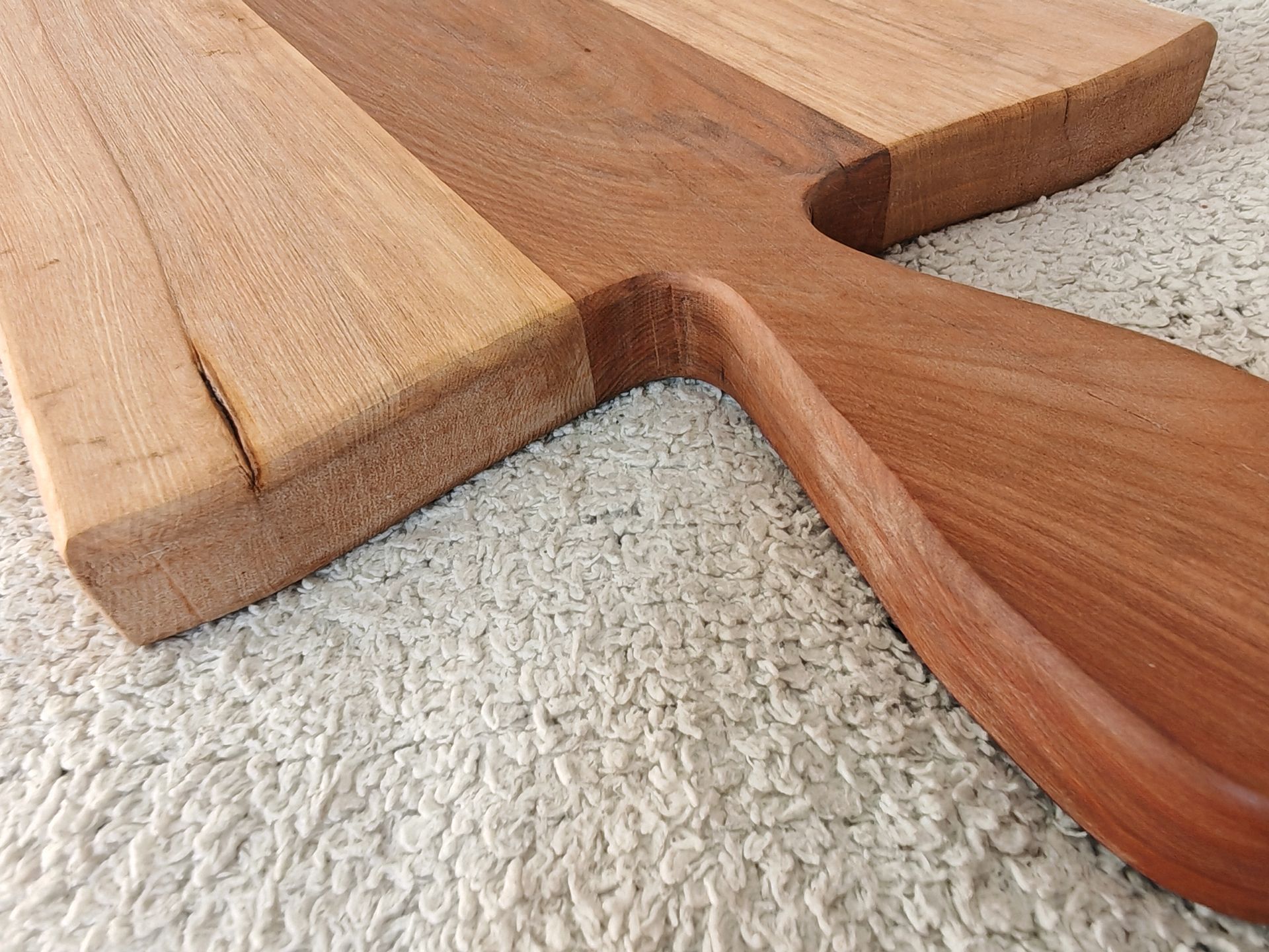 Una tabla de cortar de madera con mango está colocada sobre un mostrador.