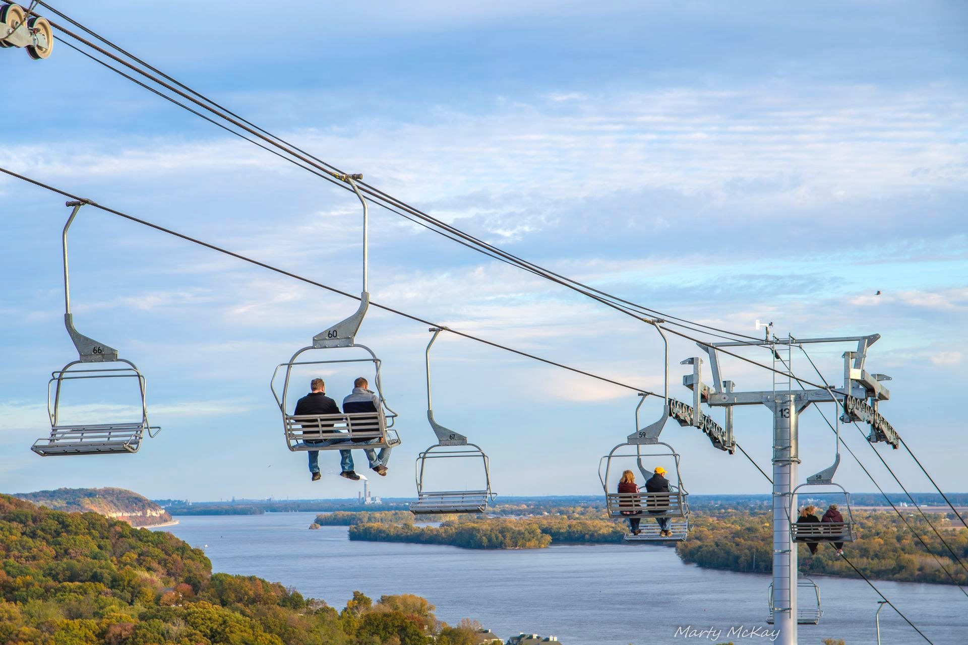 A group of people are riding a ski lift over a body of water.
