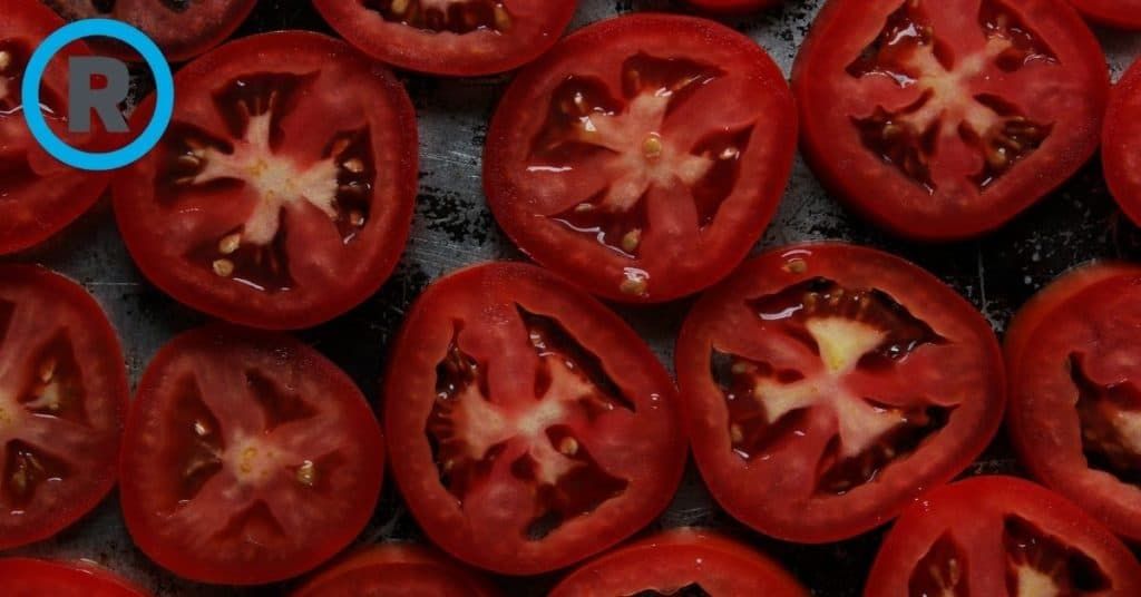 A bunch of sliced tomatoes with a blue r in the middle