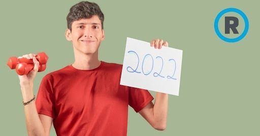 A young man is holding dumbbells and a sign that says 2022.