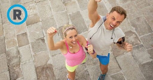 A man and a woman are standing next to each other with their arms in the air.