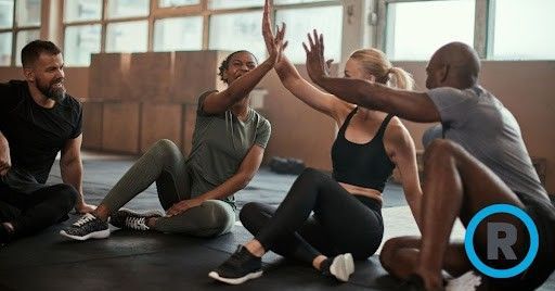 A group of people are sitting on the floor giving each other a high five.