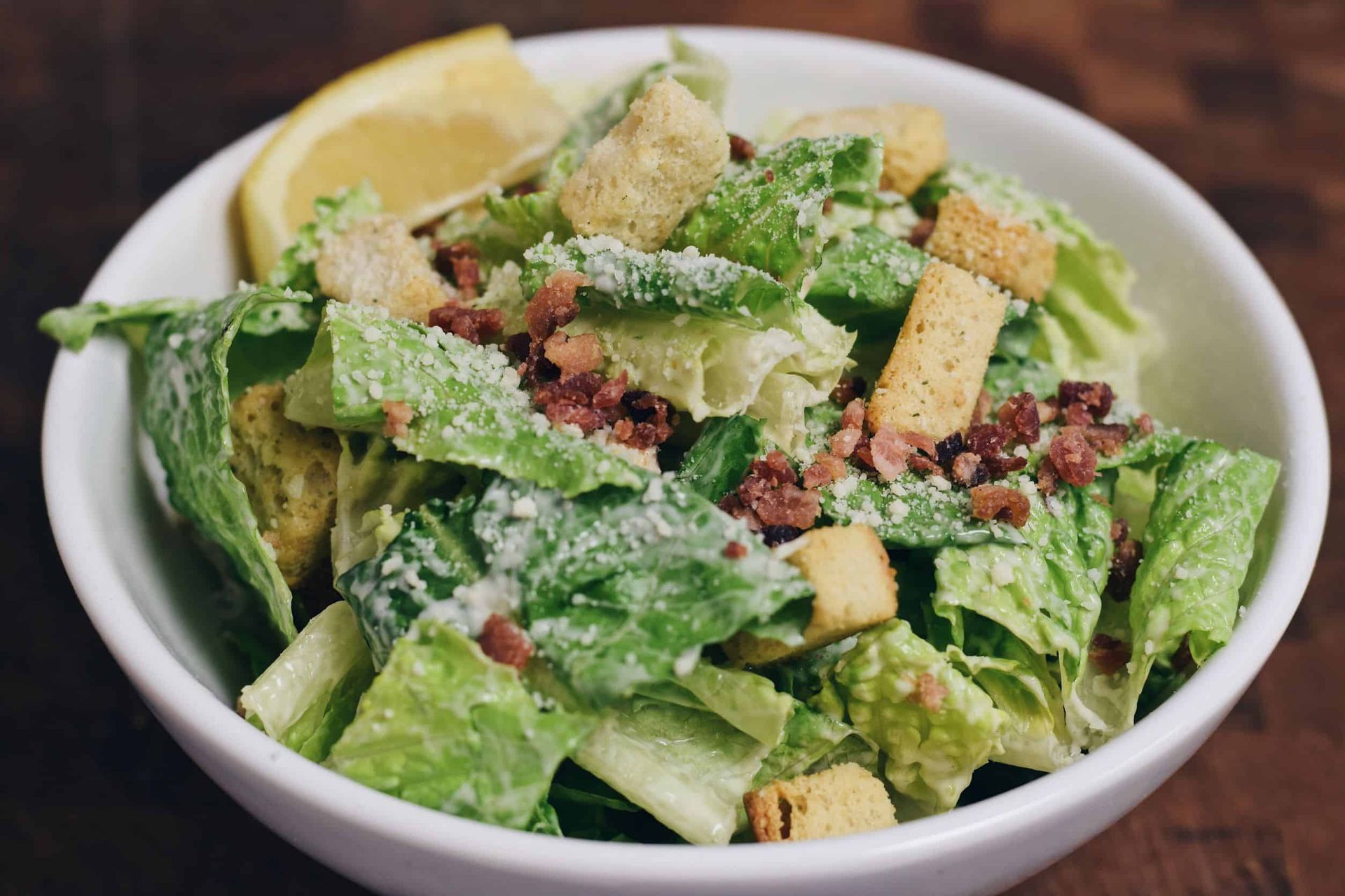 A close up of a caesar salad in a bowl on a table.