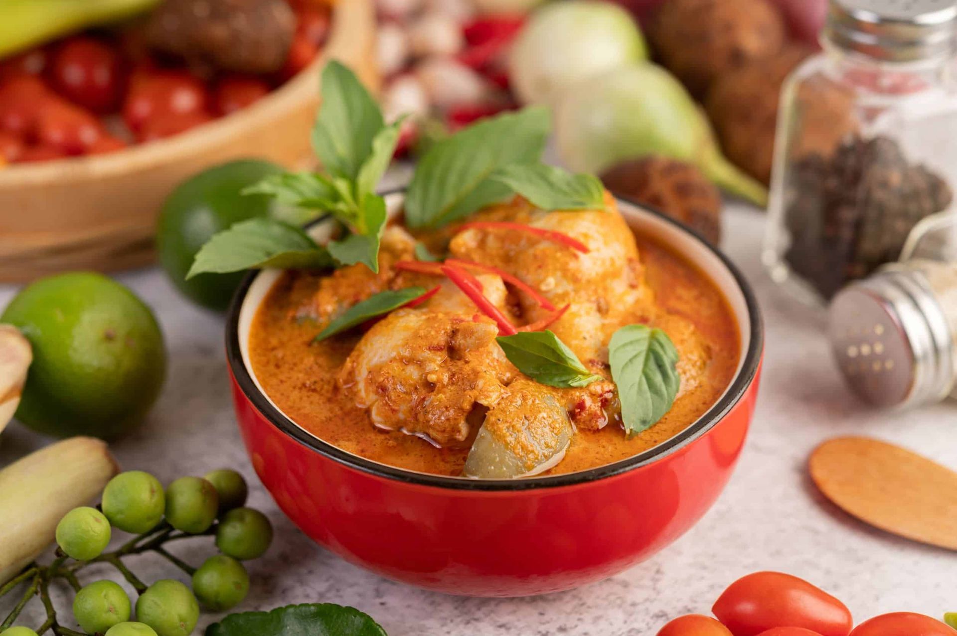 A bowl of chicken curry with vegetables on a table.