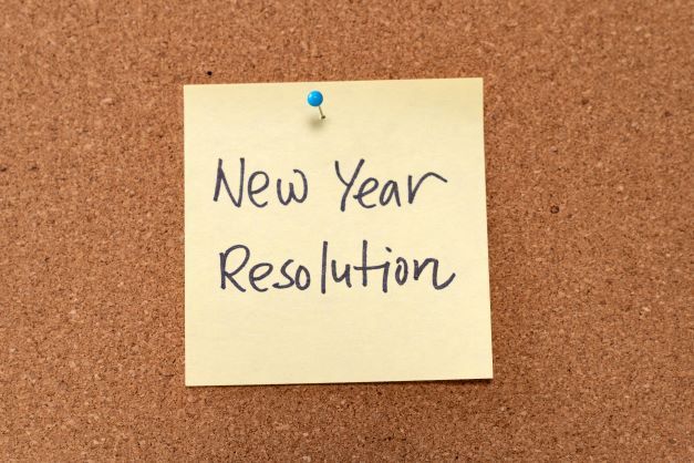 A sticky note on a cork board that says new year resolution