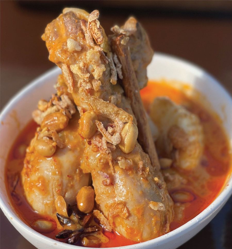 A bowl of chicken and peanuts in a sauce