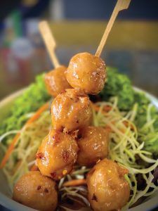 A close up of a plate of food with meatballs on sticks.