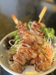 A plate of food with meat and vegetables on skewers on a table.