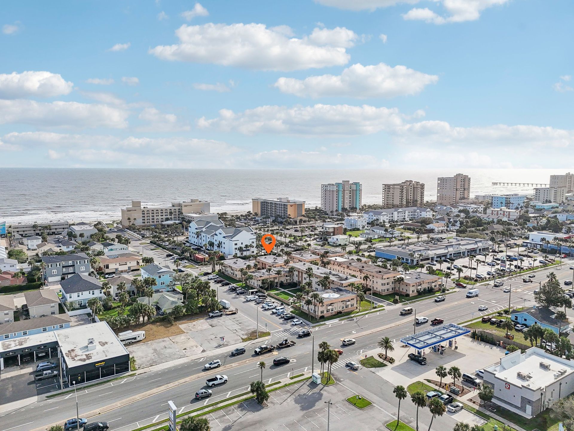 Aerial view of a coastal town with buildings, roads, and the ocean under a cloudy sky.