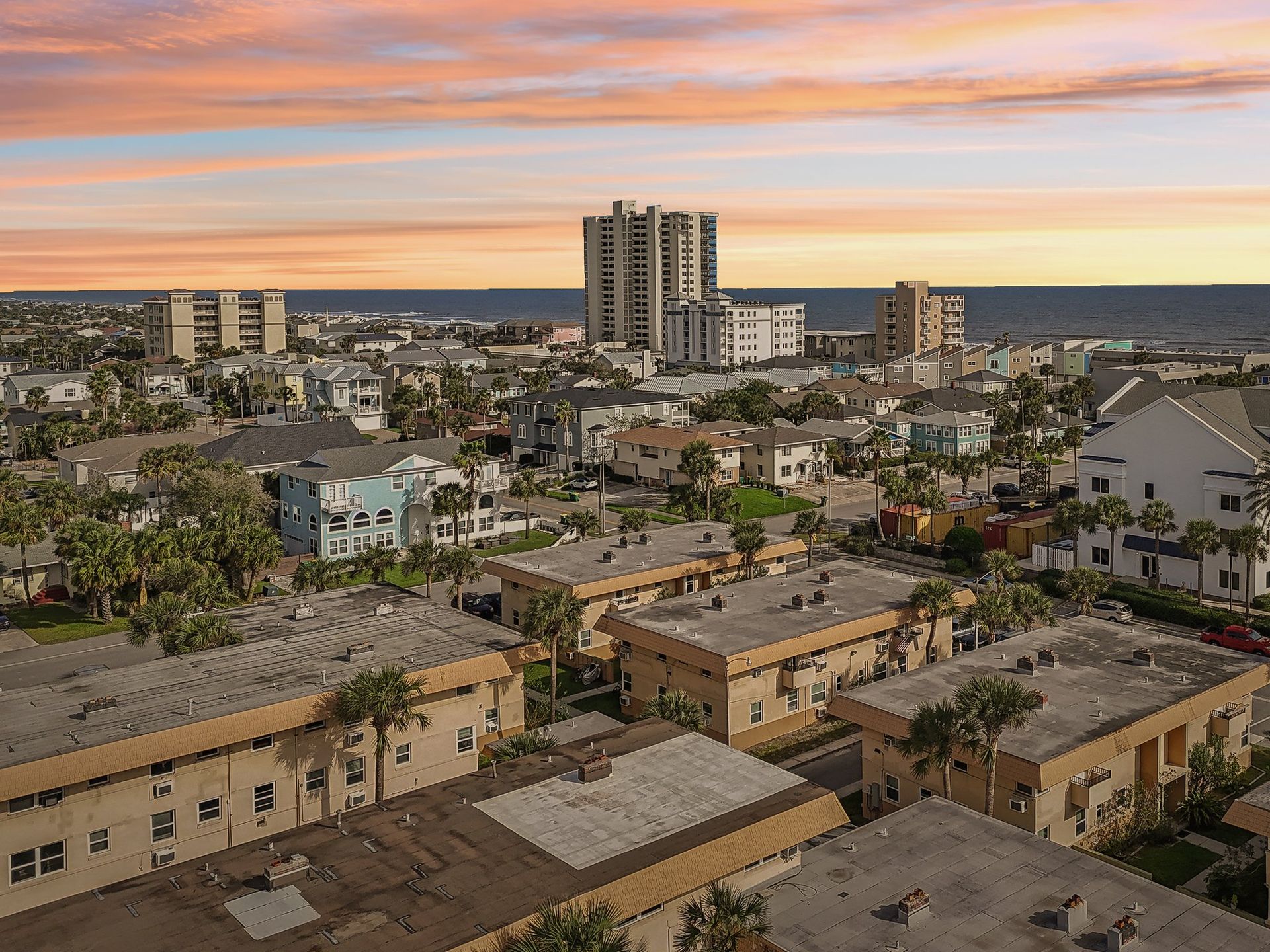 City skyline with buildings, sunset sky over ocean.