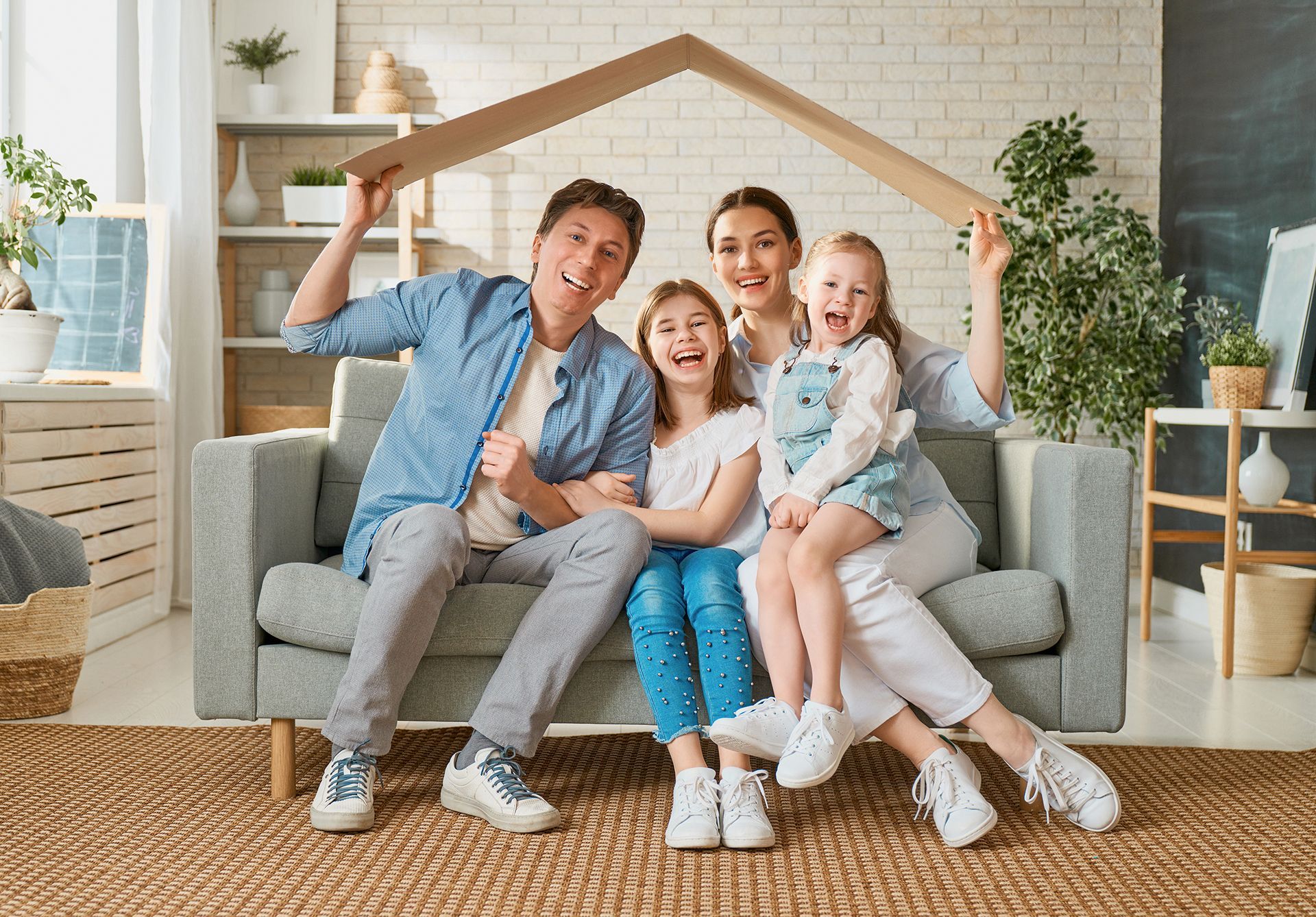 A family is sitting on a couch under a cardboard house.