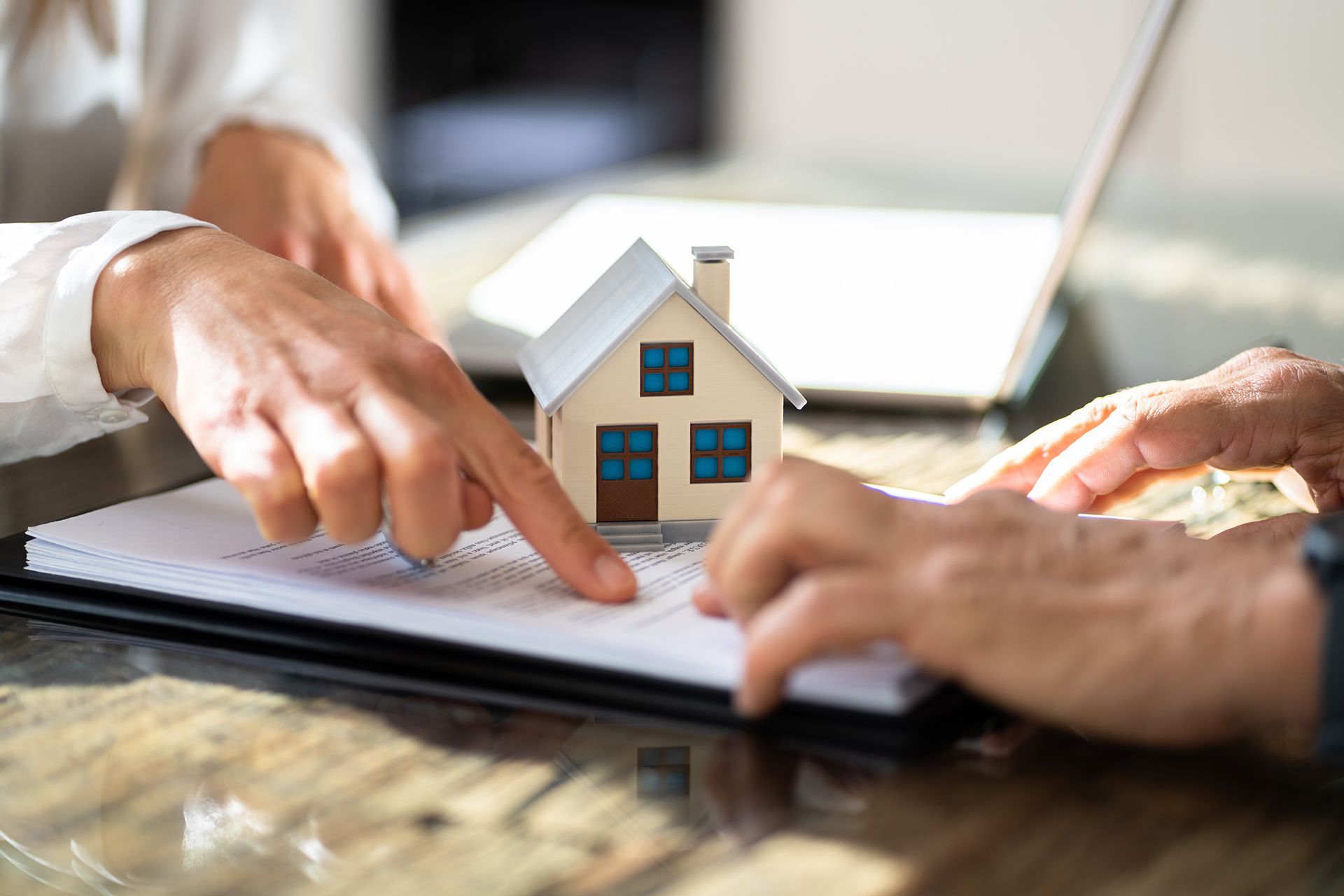 A man is pointing at a model house on a piece of paper.