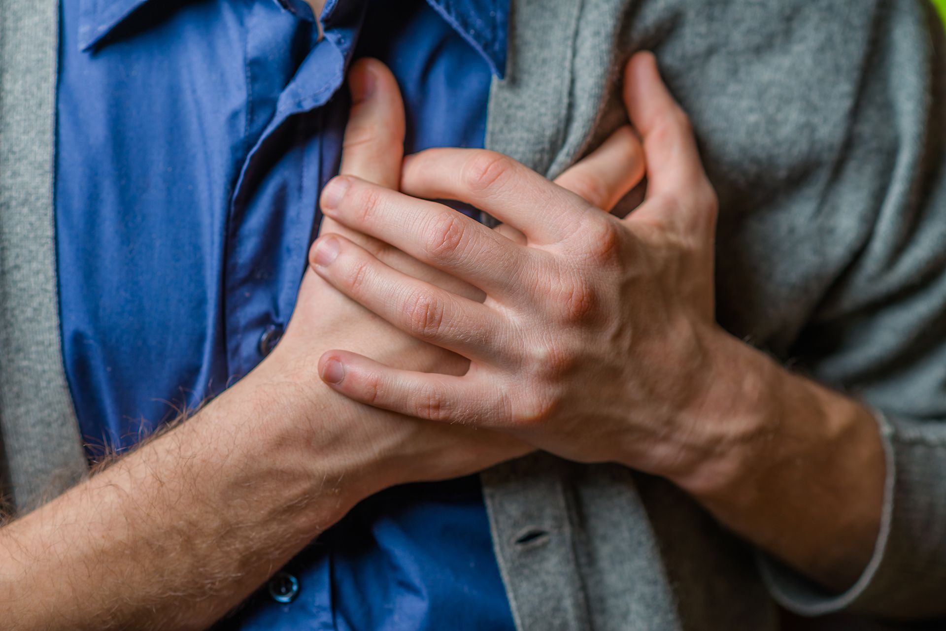 A man is holding his chest in pain because he has a heart attack.