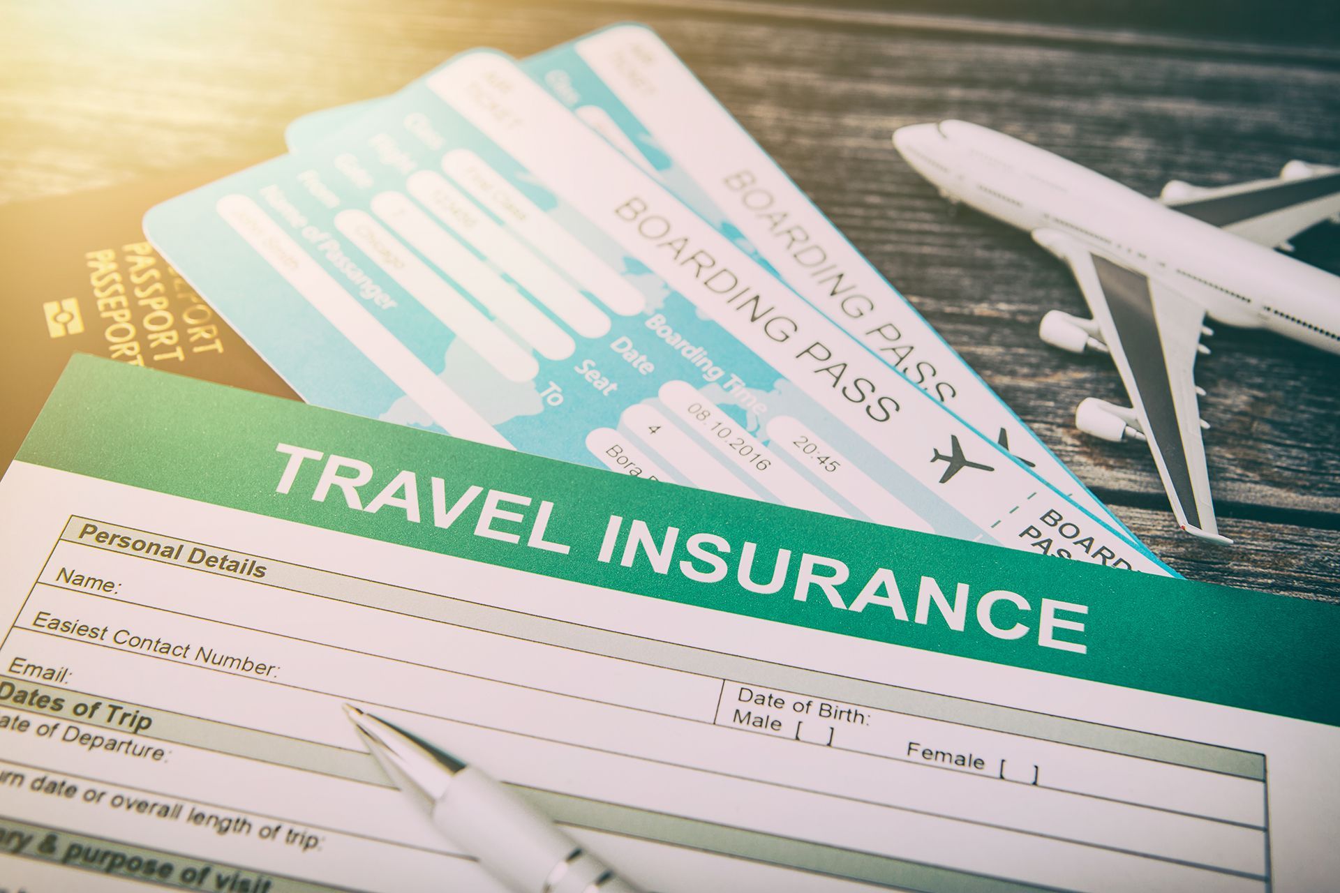 A stack of boarding passes and a travel insurance form on a wooden table.