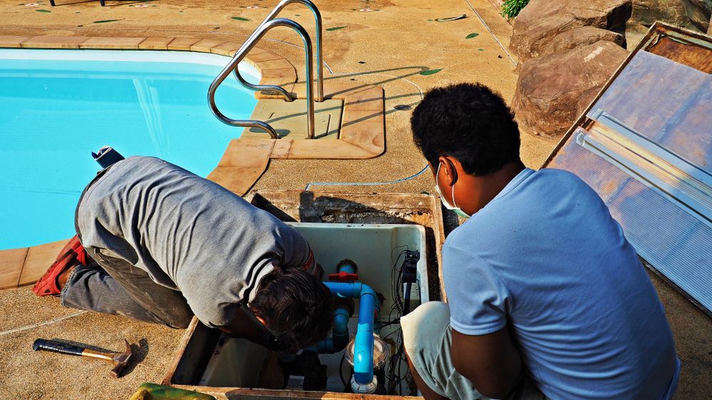 Two People Working on Pool Plumbing in a Tiled Enclosure Beside a Pool — Port Douglas Pool Shop in Craiglie, QLD