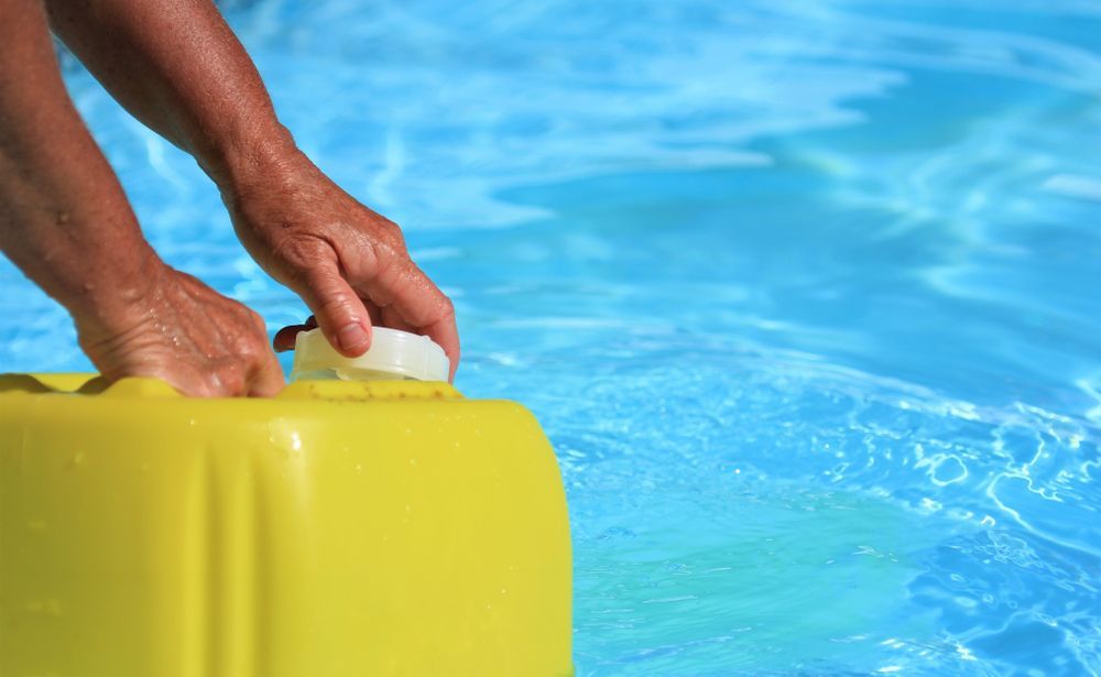 Hands Open a Yellow Container Next to a Blue Swimming Pool — Port Douglas Pool Shop in Cape Tribulation, QLD