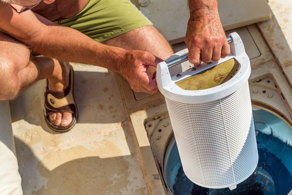 Person Removing a Basket Filter From a Pool Skimmer — Port Douglas Pool Shop in Cape Tribulation, QLD
