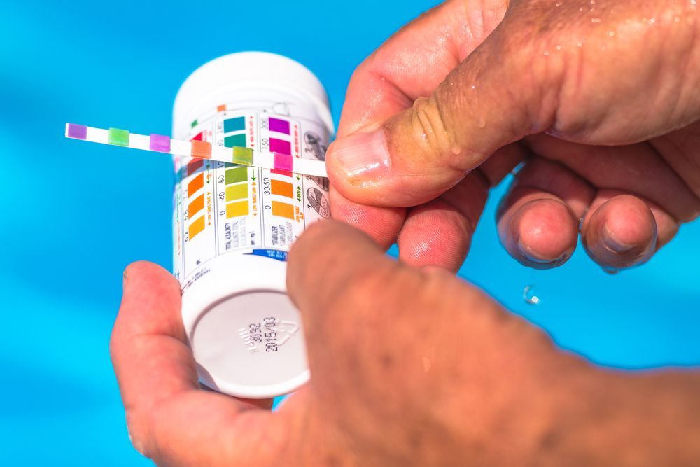 Hands Holding a Pool Water Testing Strip Next to a Color Chart — Port Douglas Pool Shop in Craiglie, QLD