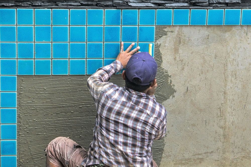 Person Tiling Pool Wall With Blue Tiles, Outdoors — Port Douglas Pool Shop in Daintree, QLD