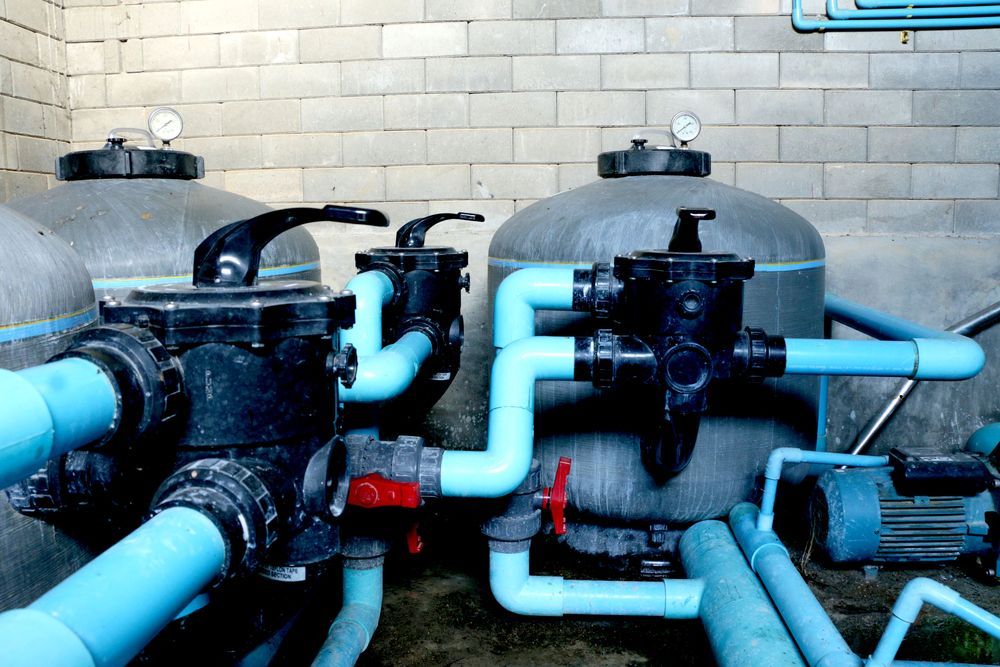 Pool Filter Equipment With Blue Pipes and Tanks Against a Cinder Block Wall — Port Douglas Pool Shop in Craiglie, QLD