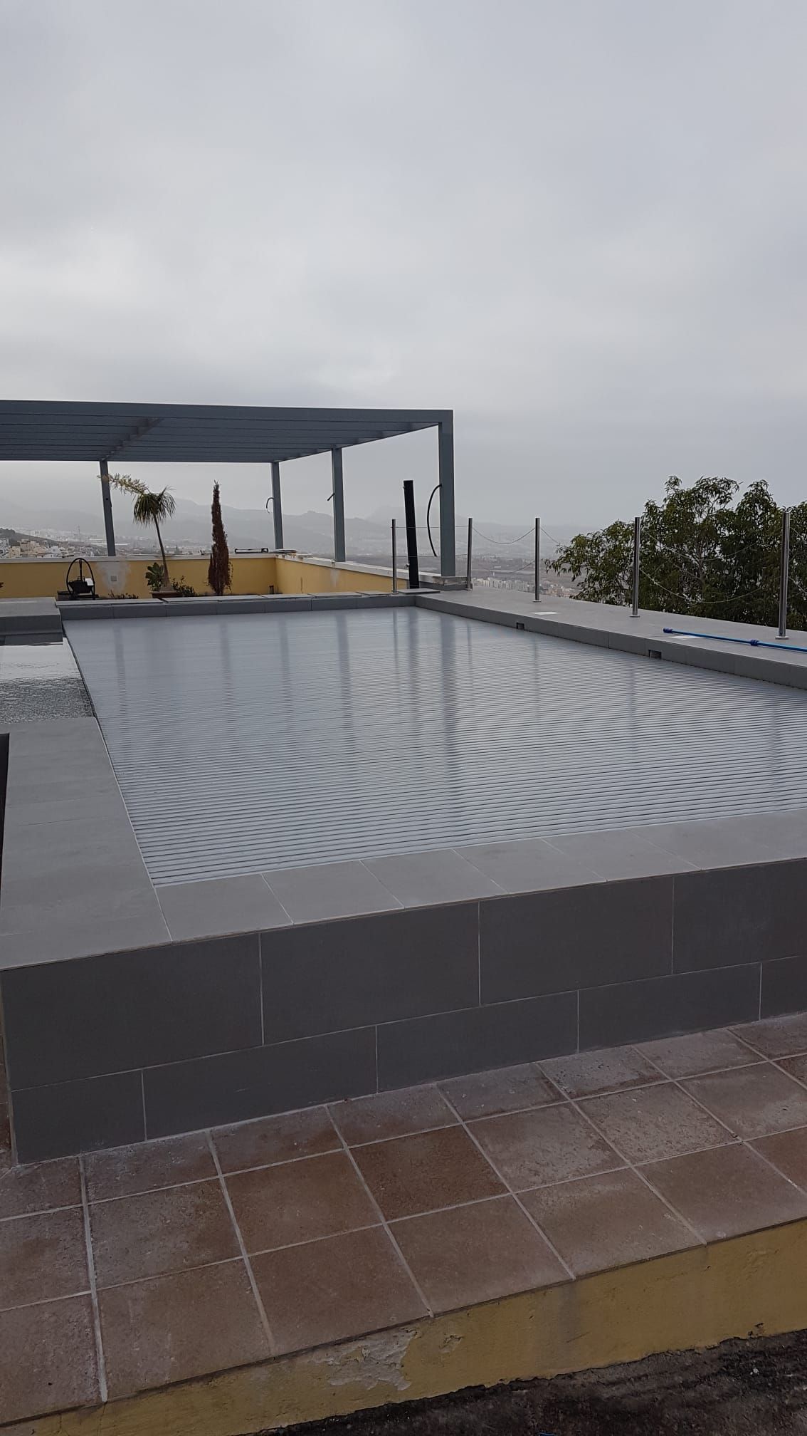 Rooftop Rectangular Pool With Gray Tile and Water, Cloudy Sky, Metal Pergola — Port Douglas Pool Shop in Cape Tribulation, QLD