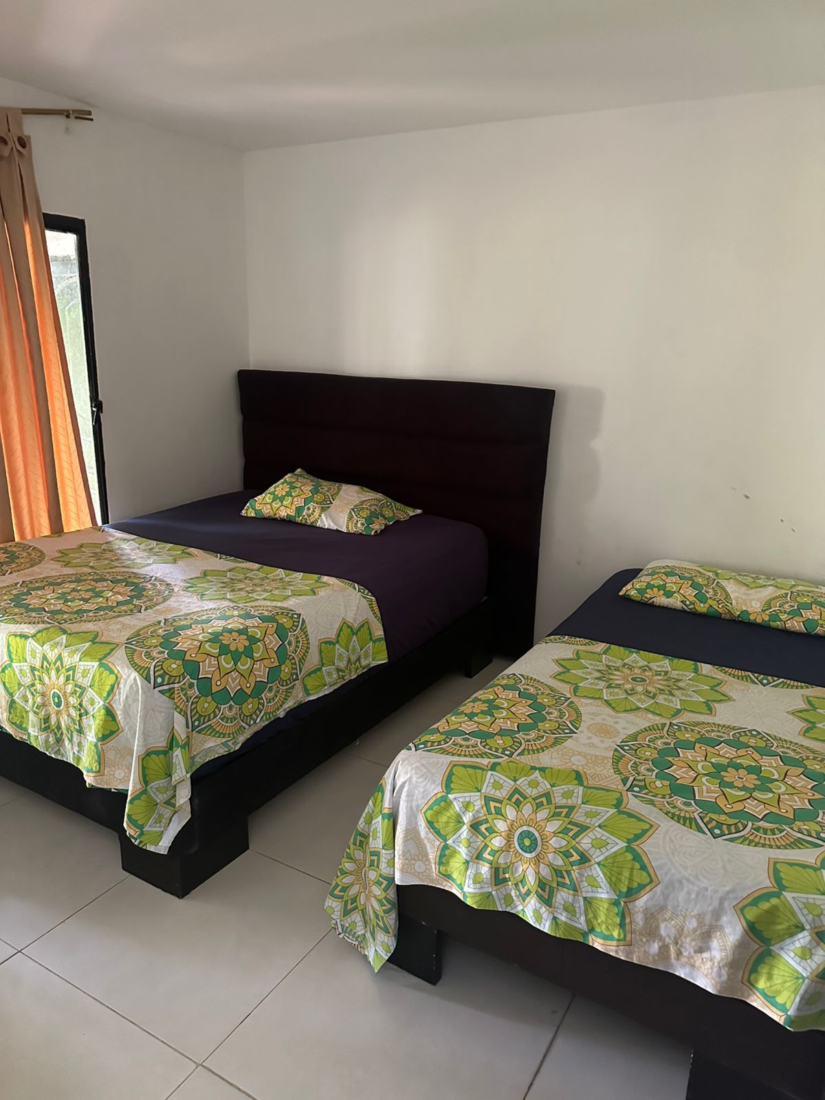 Dos camas con mantas con estampados florales en una habitación luminosa de paredes blancas.