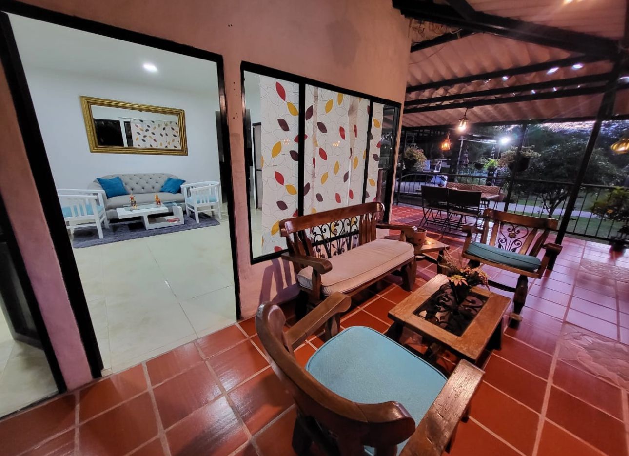 Porche al aire libre con muebles de madera, con vistas a un patio e interior con sofá y obras de arte.