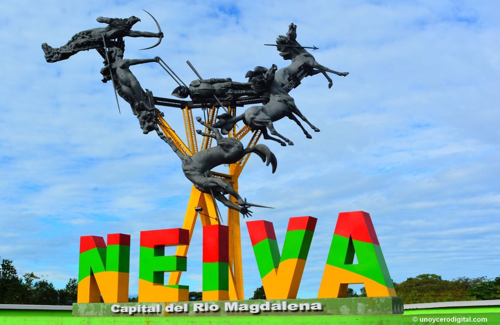 Un grupo posa junto a una formación rocosa en Guatapé, Colombia. La gente lleva sombreros blancos y sostiene una pancarta.