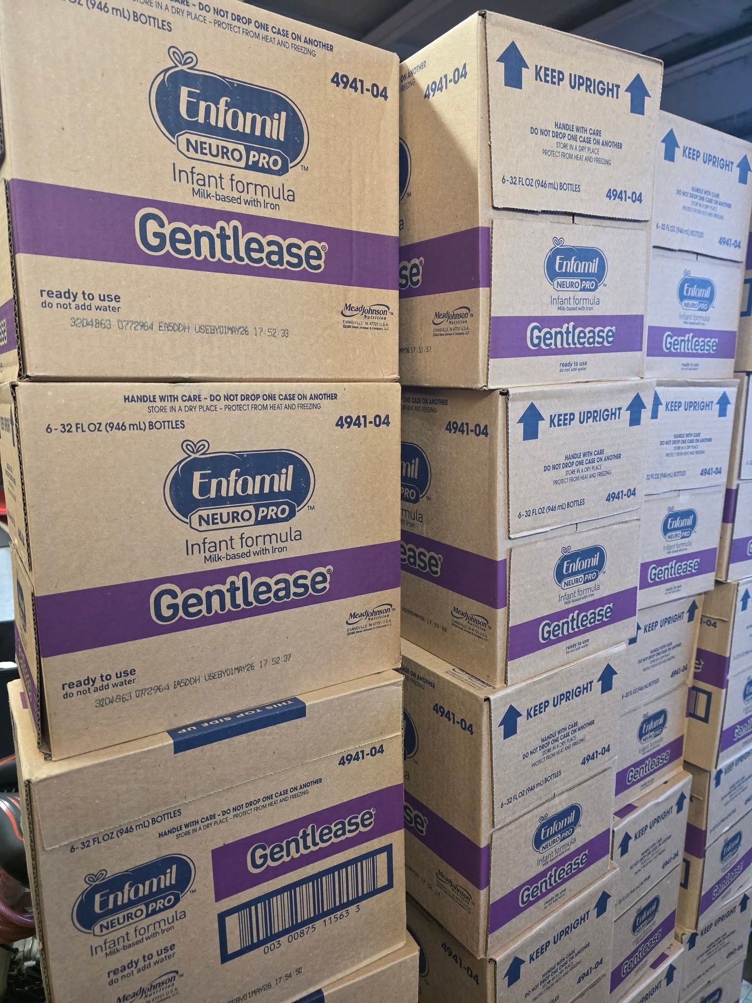 A stack of brown cardboard boxes labeled Enfamil Gentlease infant formula, arranged in a warehouse setting.