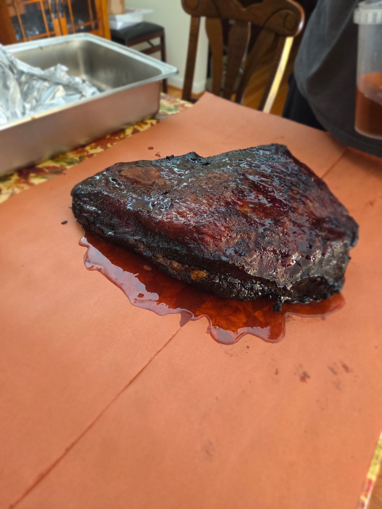 Smoked brisket on a red butcher paper. Dark, glistening bark with pooled juices.