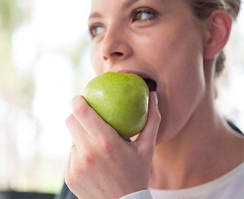 Young Woman eating a green apple