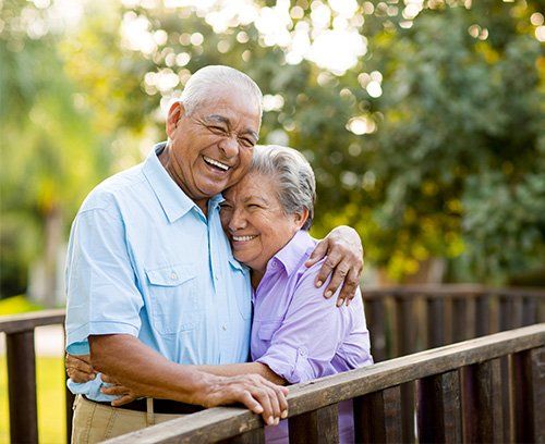 Elderly couple smiling after receiving partial dentures