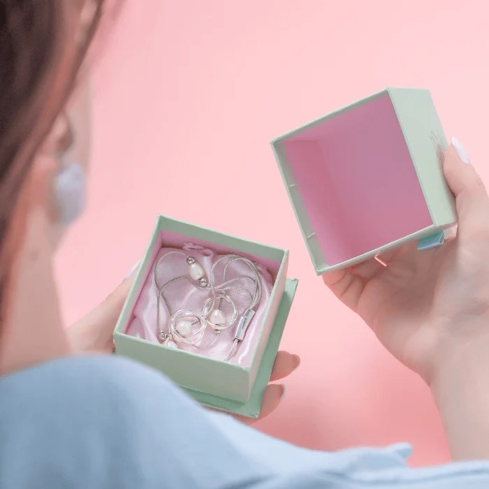 A woman is holding a box with a pair of earrings in it.
