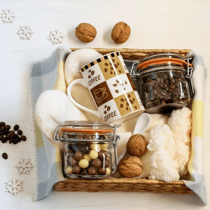 A basket filled with coffee mugs and jars of coffee beans