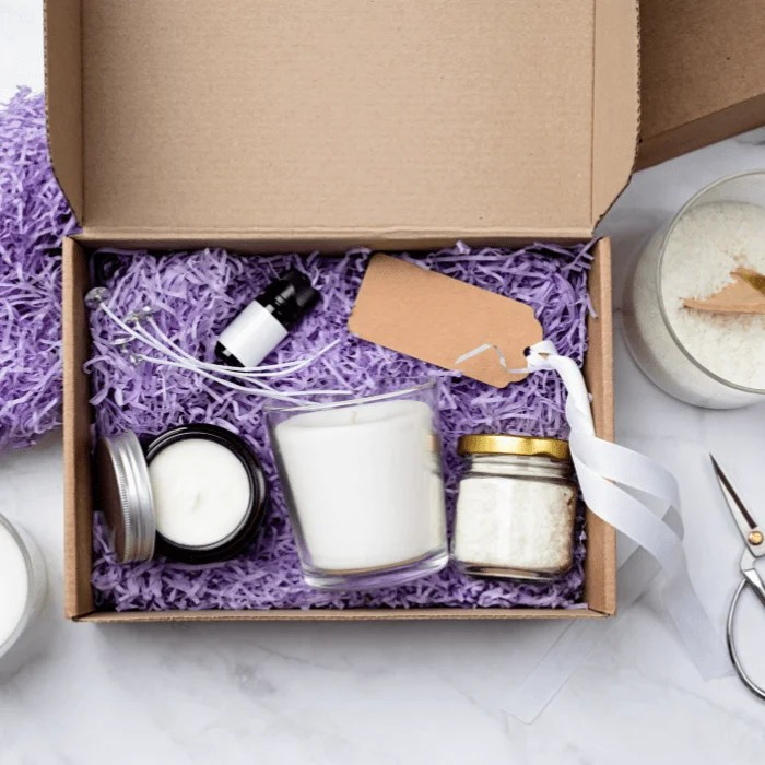 A cardboard box filled with candles and purple shredded paper