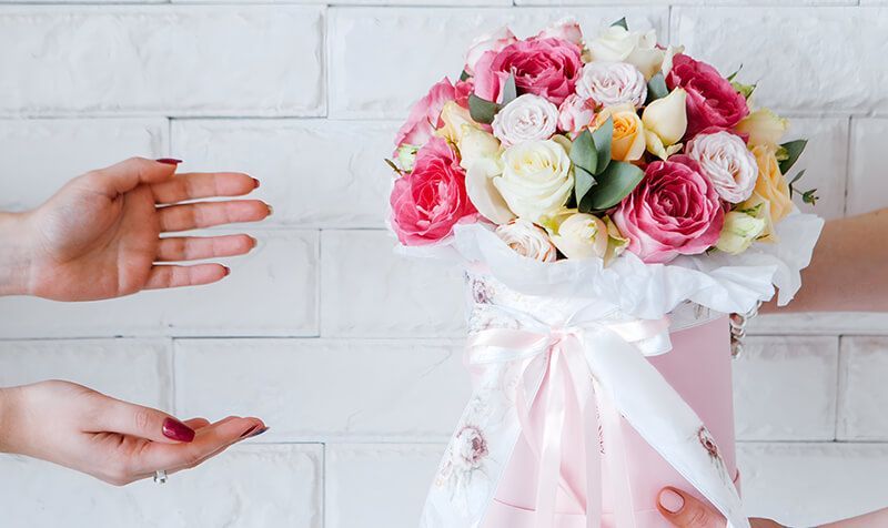 A woman is giving a bouquet of flowers to another woman.