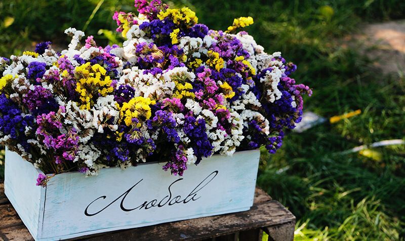 A wooden box filled with purple , yellow and white flowers.