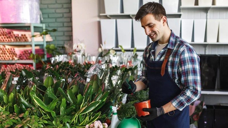 A man is watering plants in a flower shop.