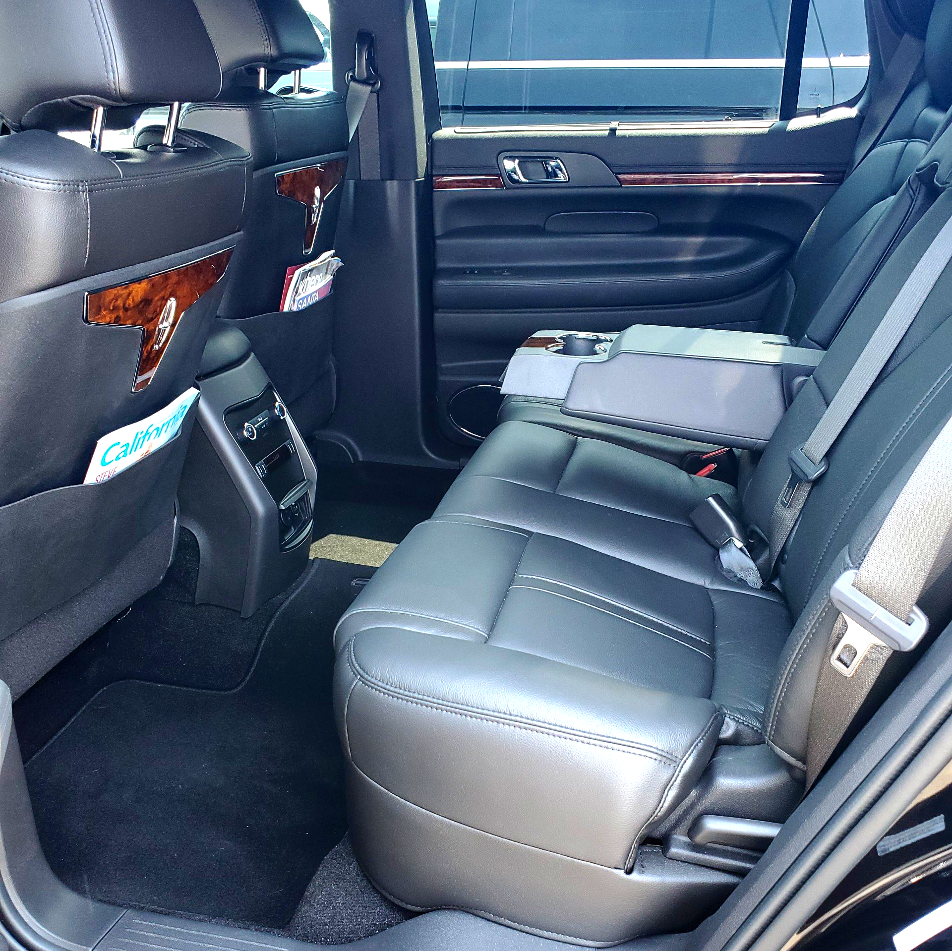The back seat of a black car has a seat belt on it
