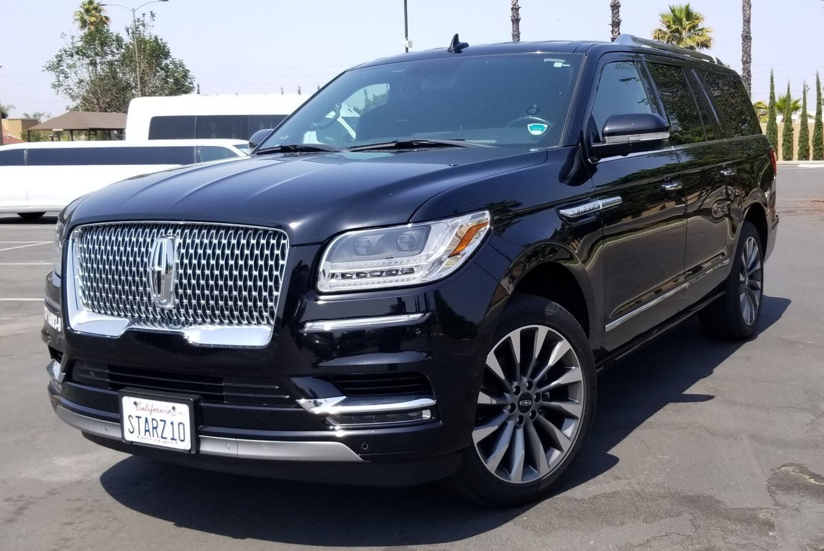 A black lincoln navigator is parked in a parking lot next to a white limousine.