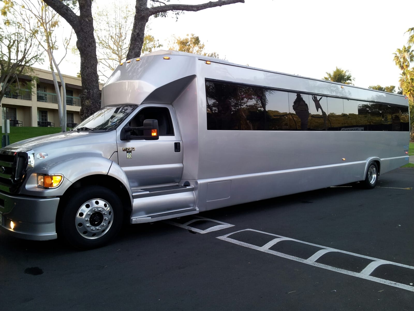 A silver limousine is parked in a parking lot