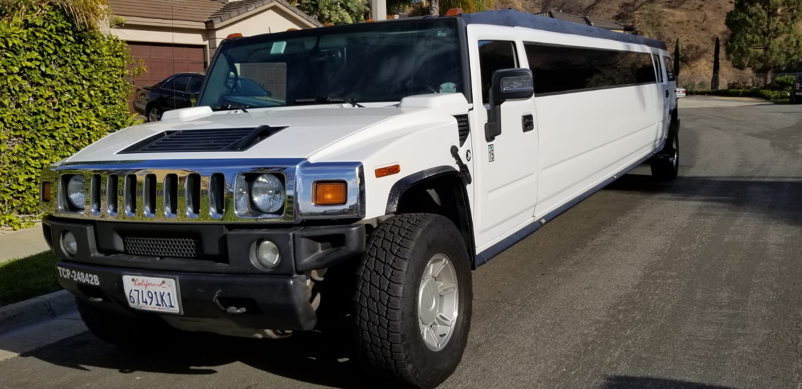 A white hummer limousine is parked on the side of the road.