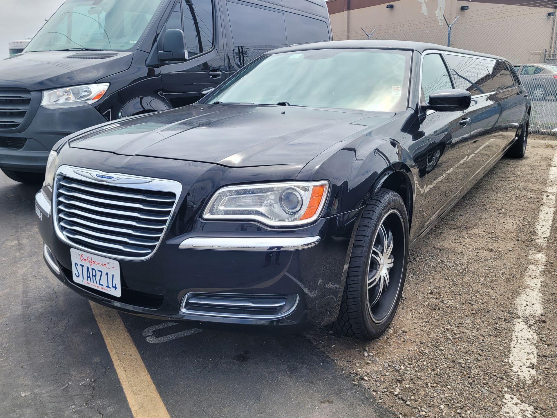 A white limousine is parked on the side of the road in front of a building.