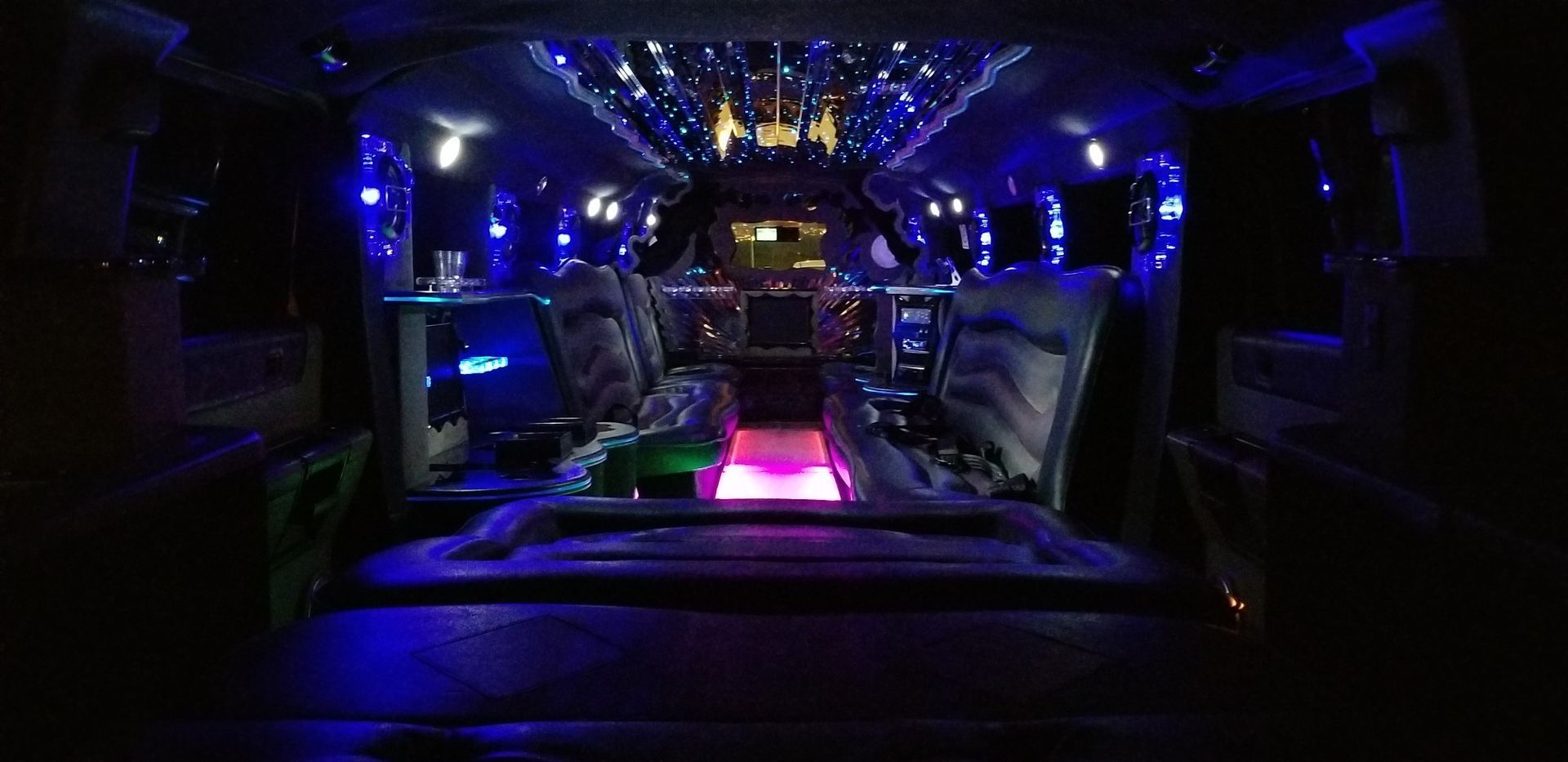 The inside of a limousine with purple lights on the ceiling.